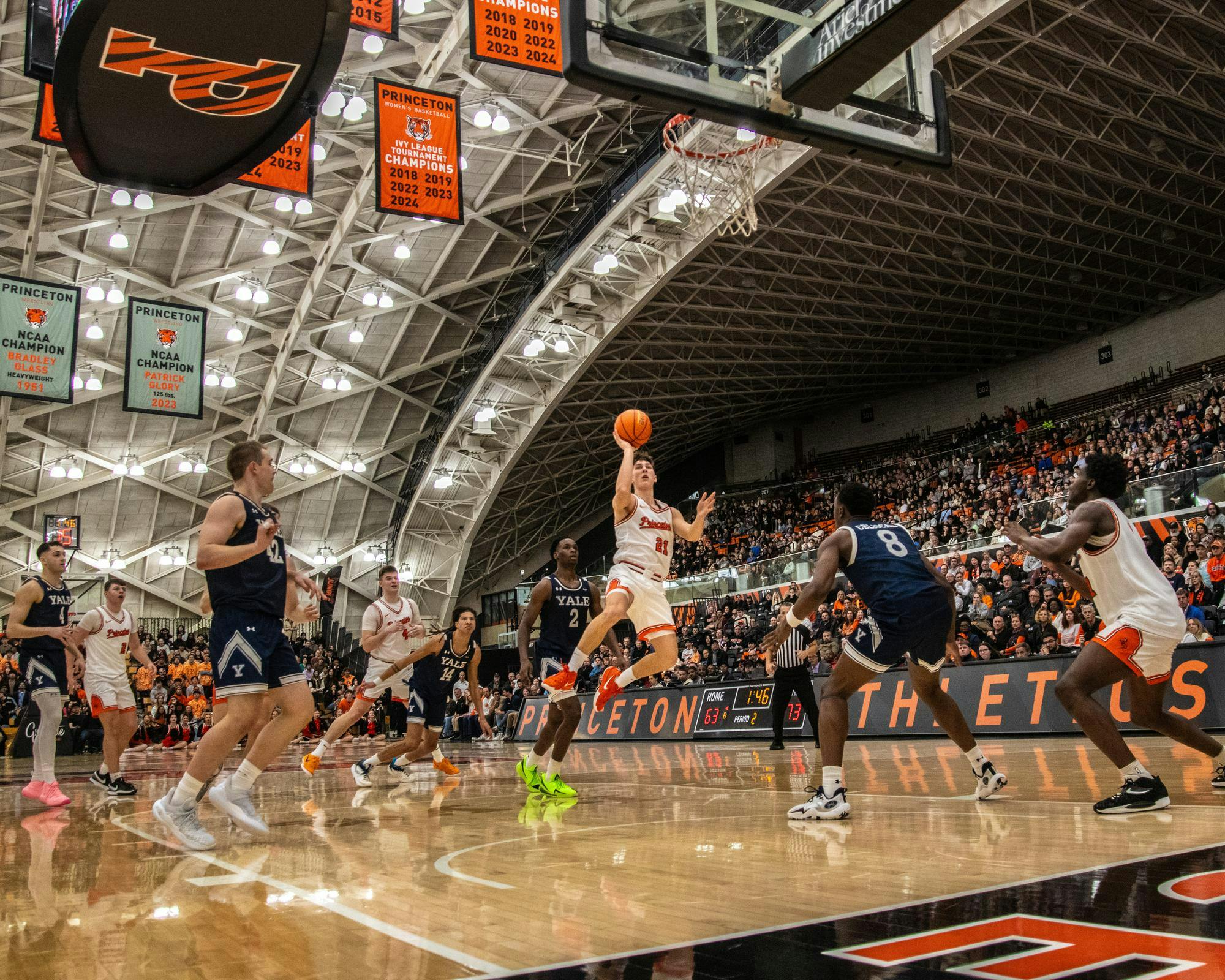 A man with a white jersey and white shorts driving in getting ready to shoot a basketball 
