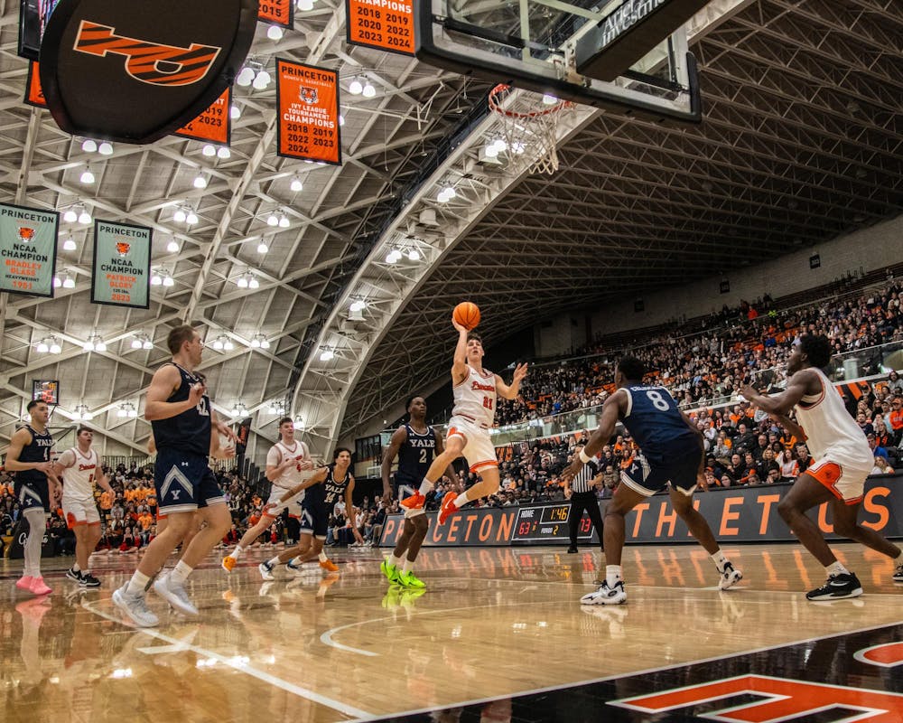 A man with a white jersey and white shorts driving in getting ready to shoot a basketball 