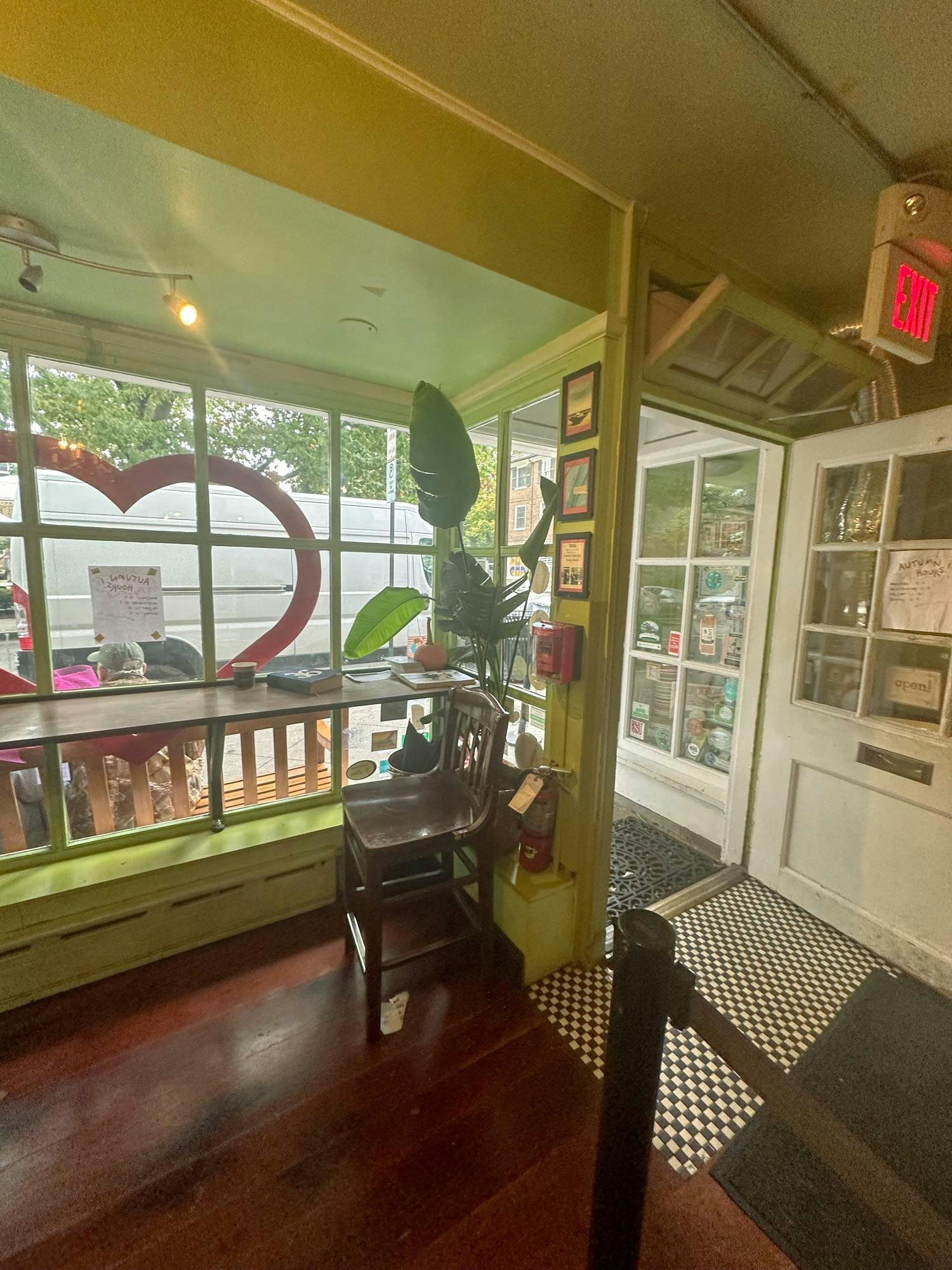 Interior of a shop with green walls, a long table, and a heart decoration on the window.