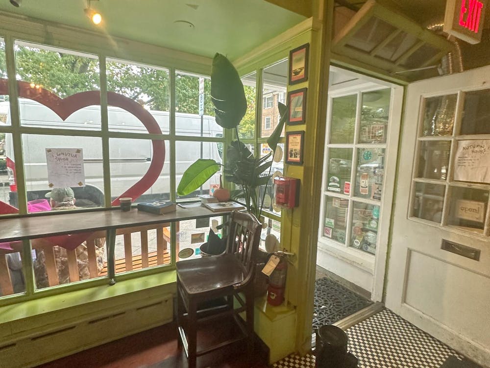 Interior of a shop with green walls, a long table, and a heart decoration on the window.