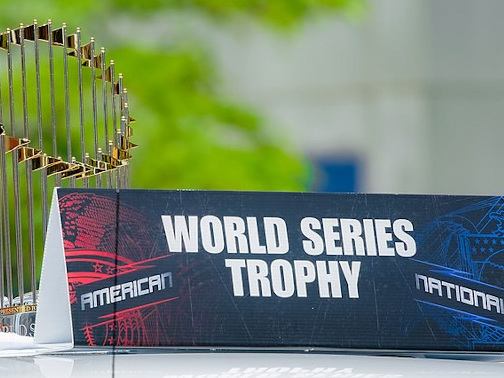 The Commissioner's Trophy of gold and silver sits behind a black, red, and blue sign that reads, 'World Series Trophy.'