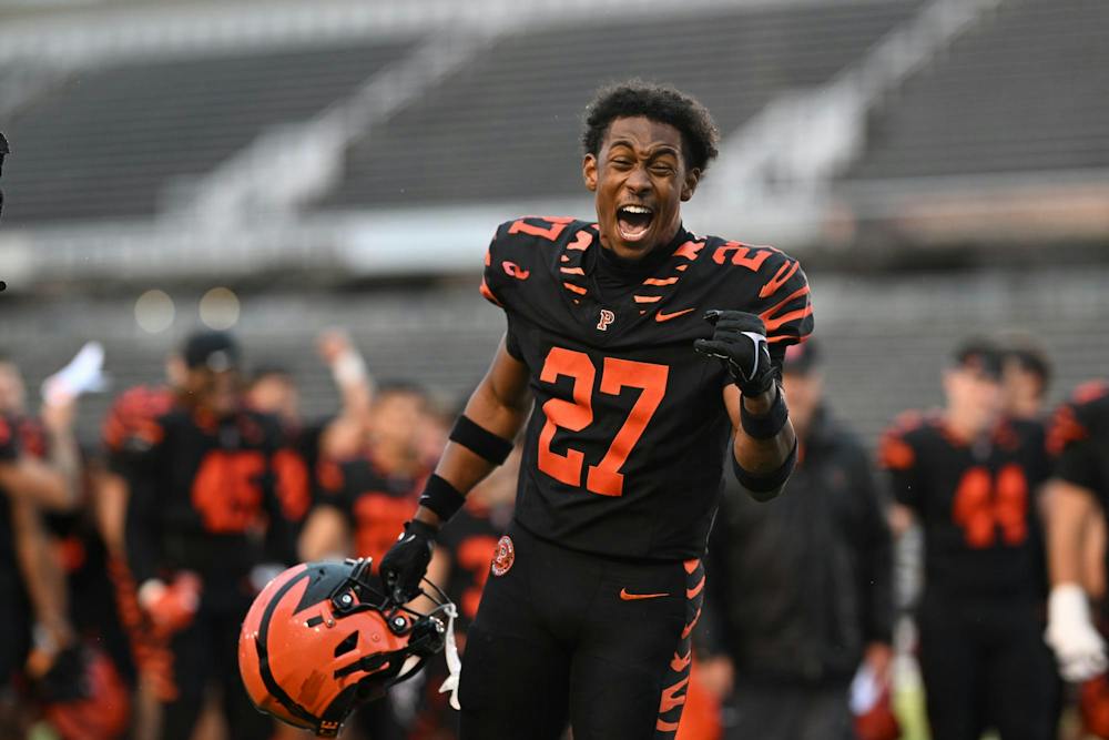 A football player in a black jersey raises his fist in celebration.