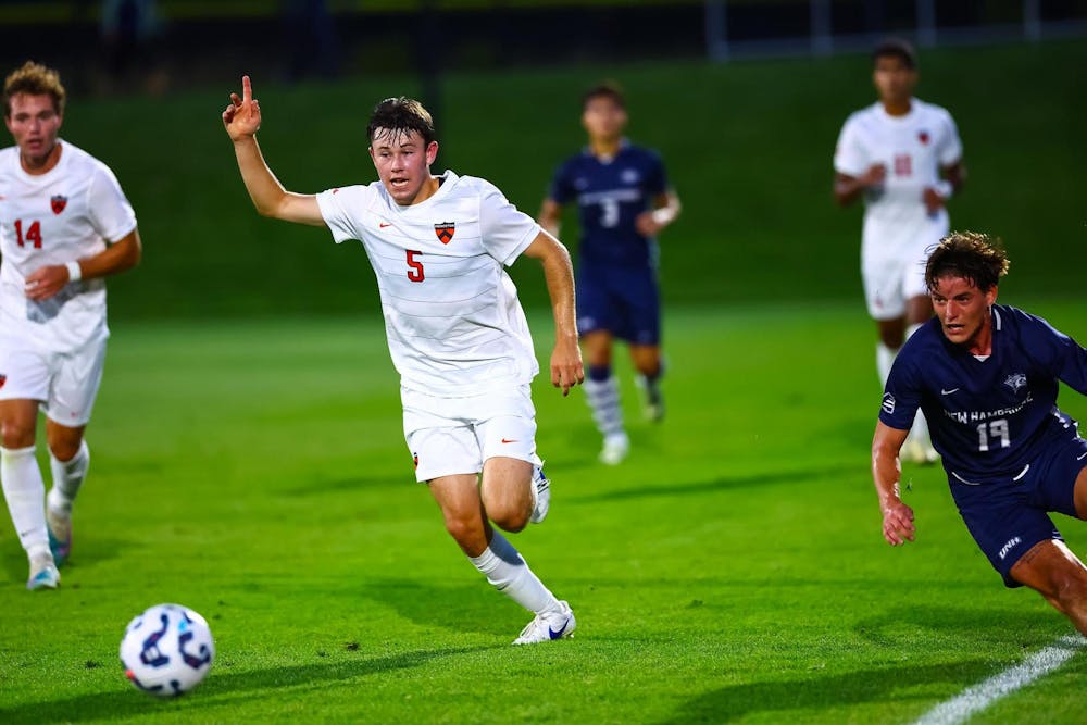 A man wearing a white jersey chasing after a ball during a soccer game on a field. 