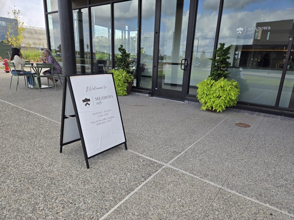 Sidewalk sign advertising a cafe in front of its doors.