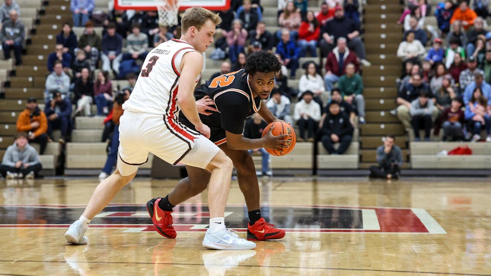 A man holding a basketball while being defended during a basketball game. 