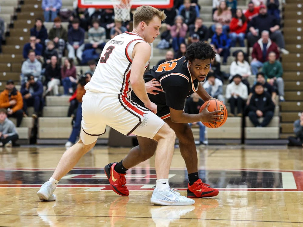 A man holding a basketball while being defended during a basketball game.