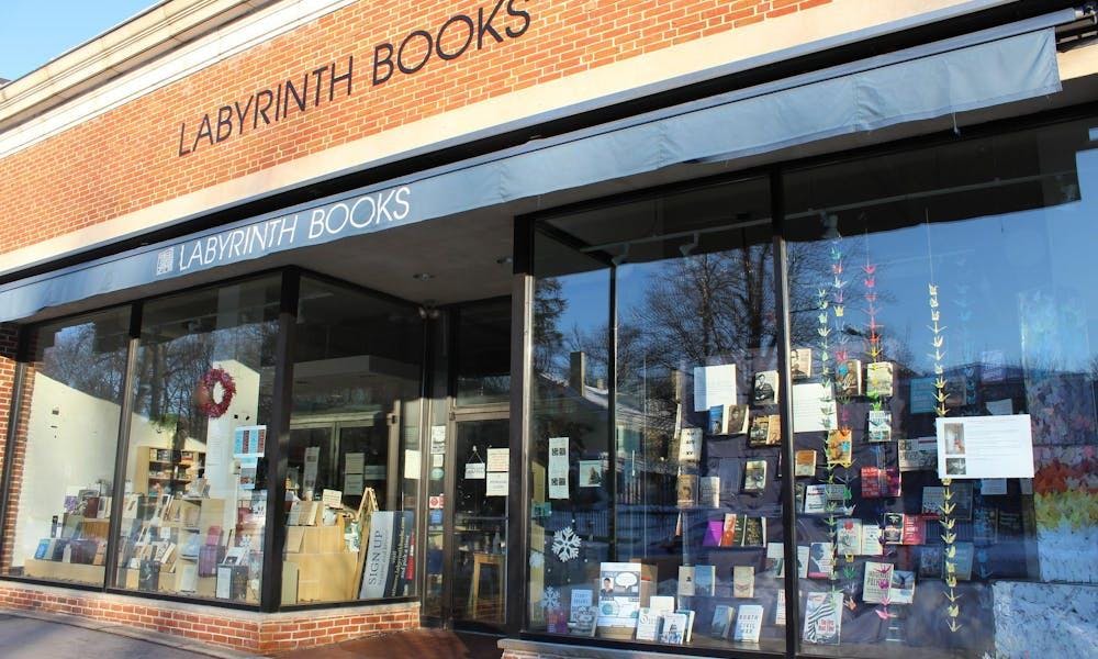 A storefront with "Labyrinth Books" printed across a blue awning. Books and strings of paper cranes are displayed in the windows.