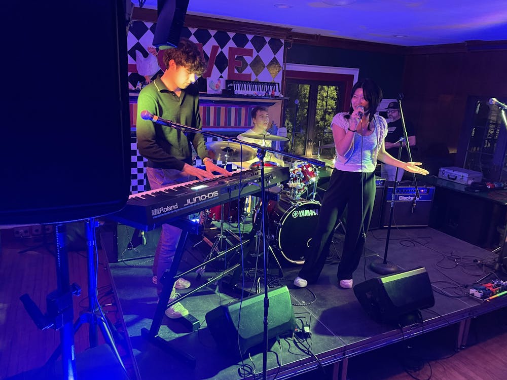 Three students play varying instruments in a dimly lit room. 