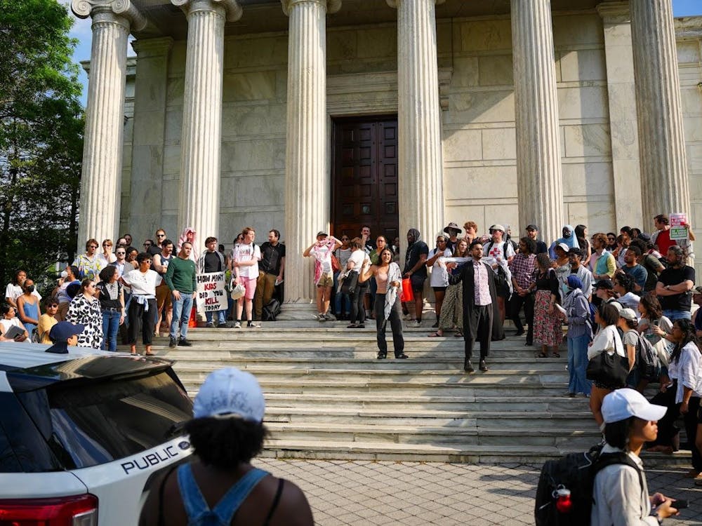 People gathered on steps in front of white building with columns holding signs