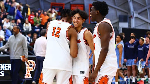 Player in white and orange basketball jersey embraces teammate 