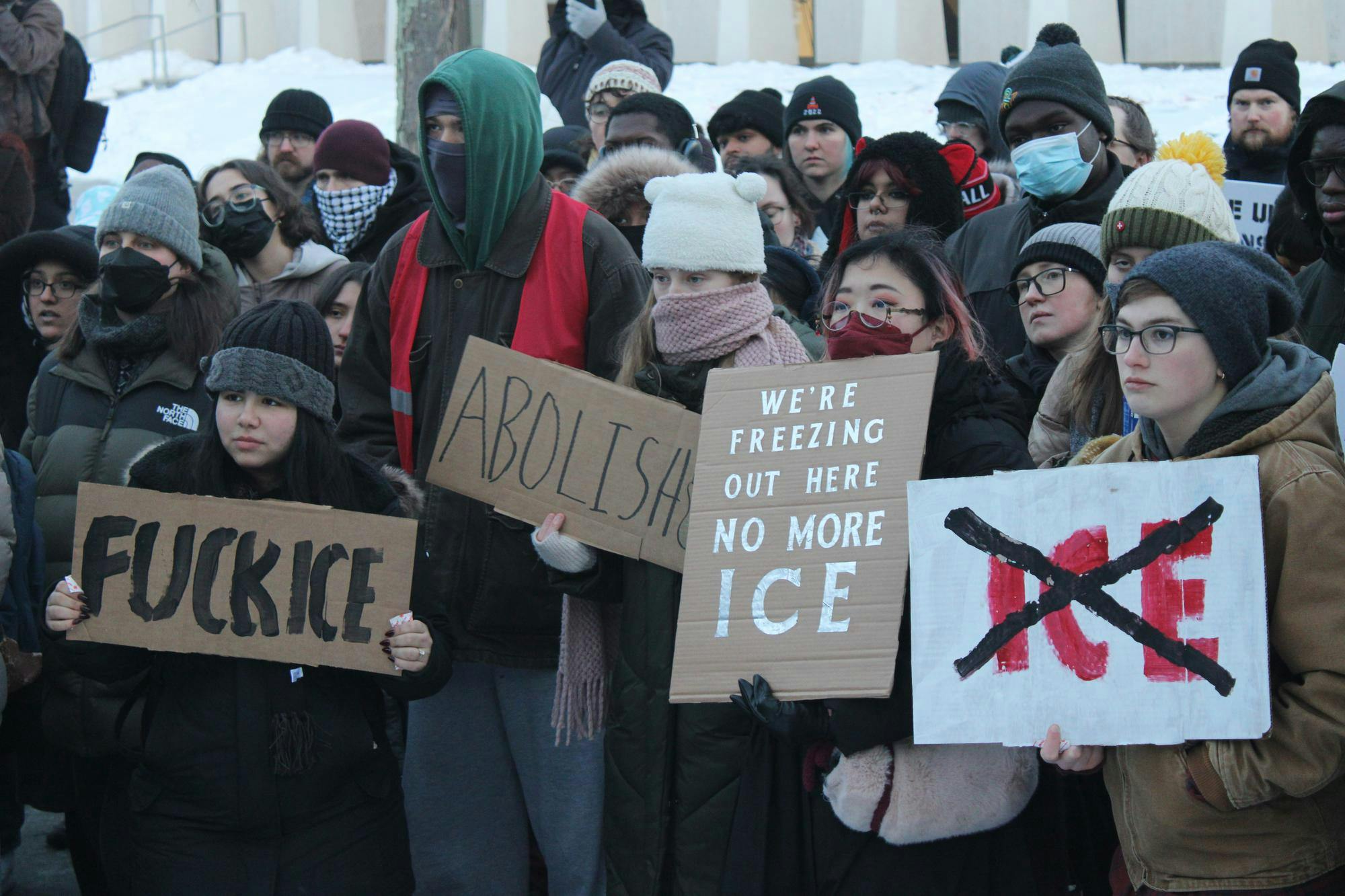 Protestors gather in front of the Fountain of Freedom holding signs opposing ICE.