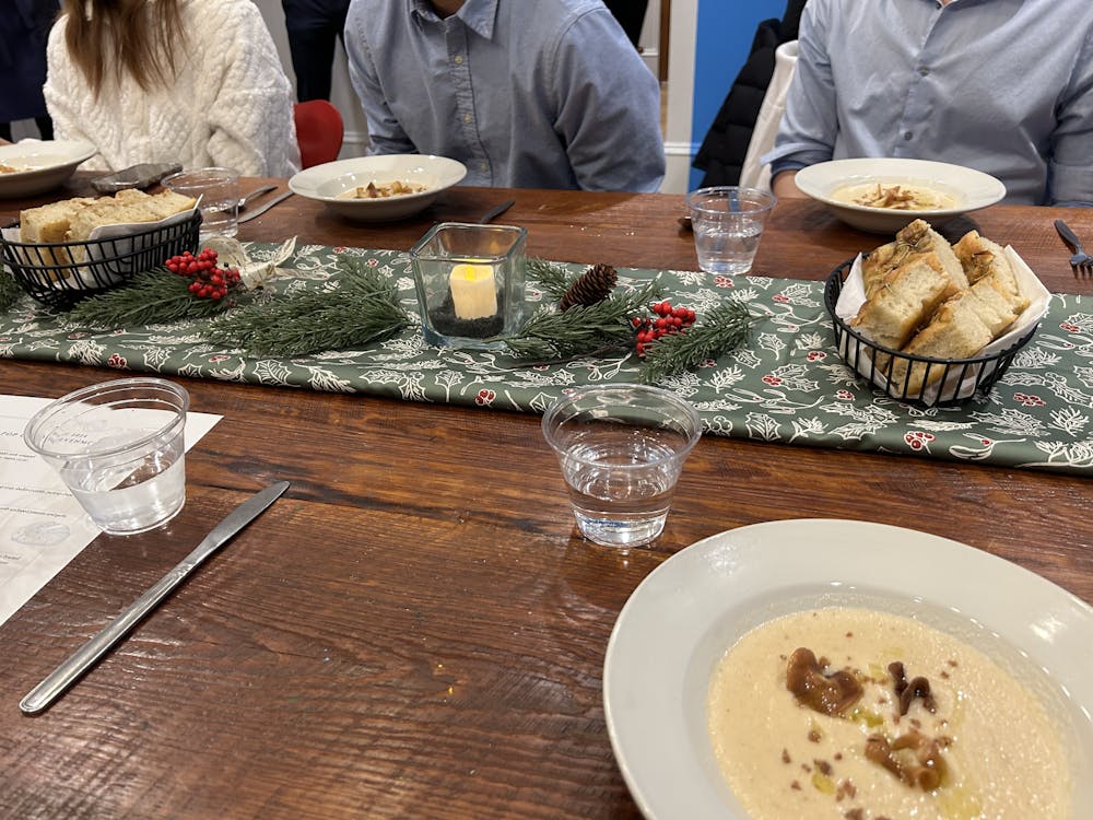Mistletoe table runner, a candle, pine needles laid out on a dark wooden dining table.