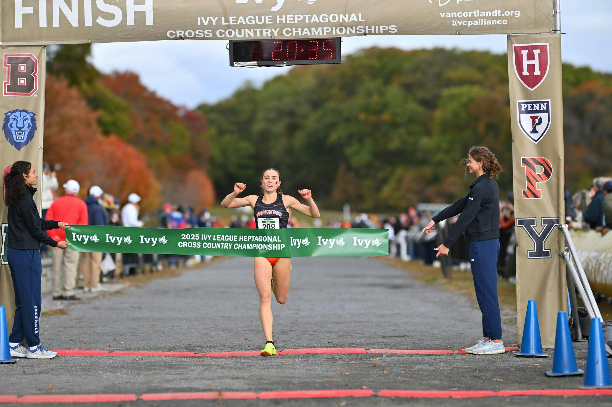 Girl in black and orange cross country suit crosses finish line