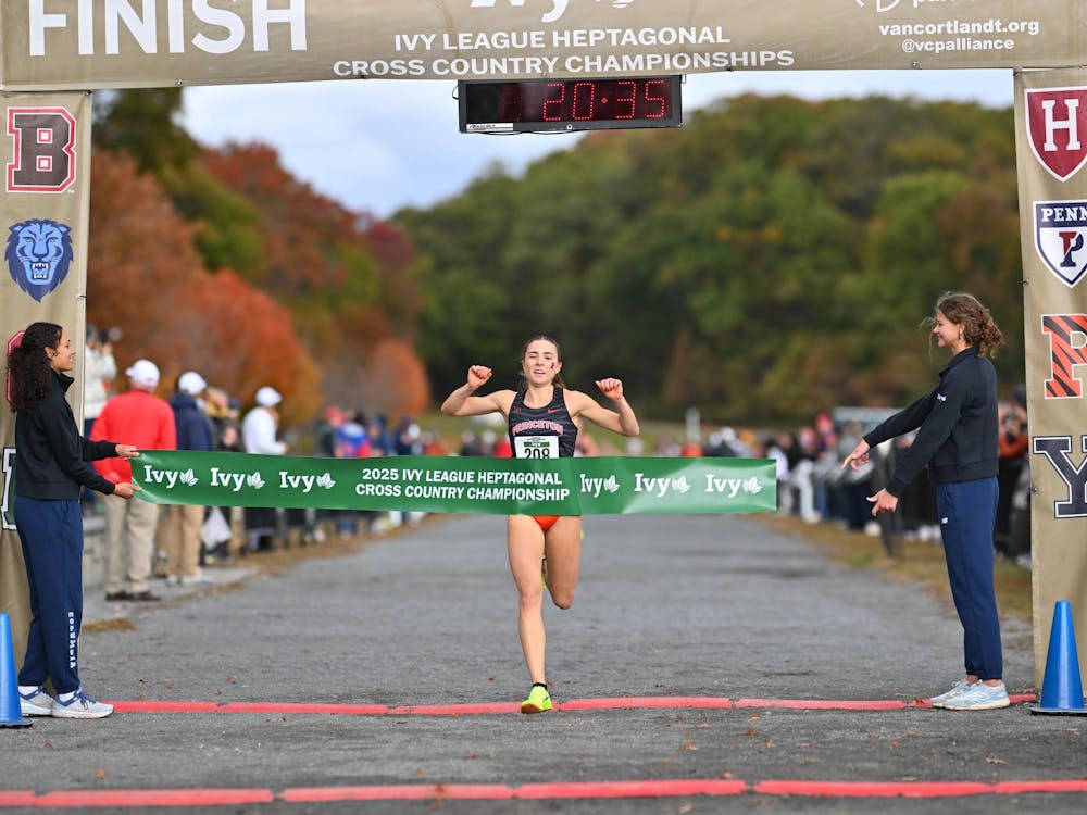 Girl in black and orange cross country suit crosses finish line