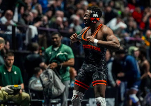 A Princeton wrestler stands in focus in front of a blurred crowd.