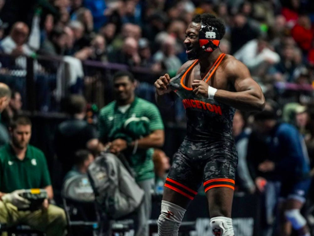 A Princeton wrestler stands in focus in front of a blurred crowd.