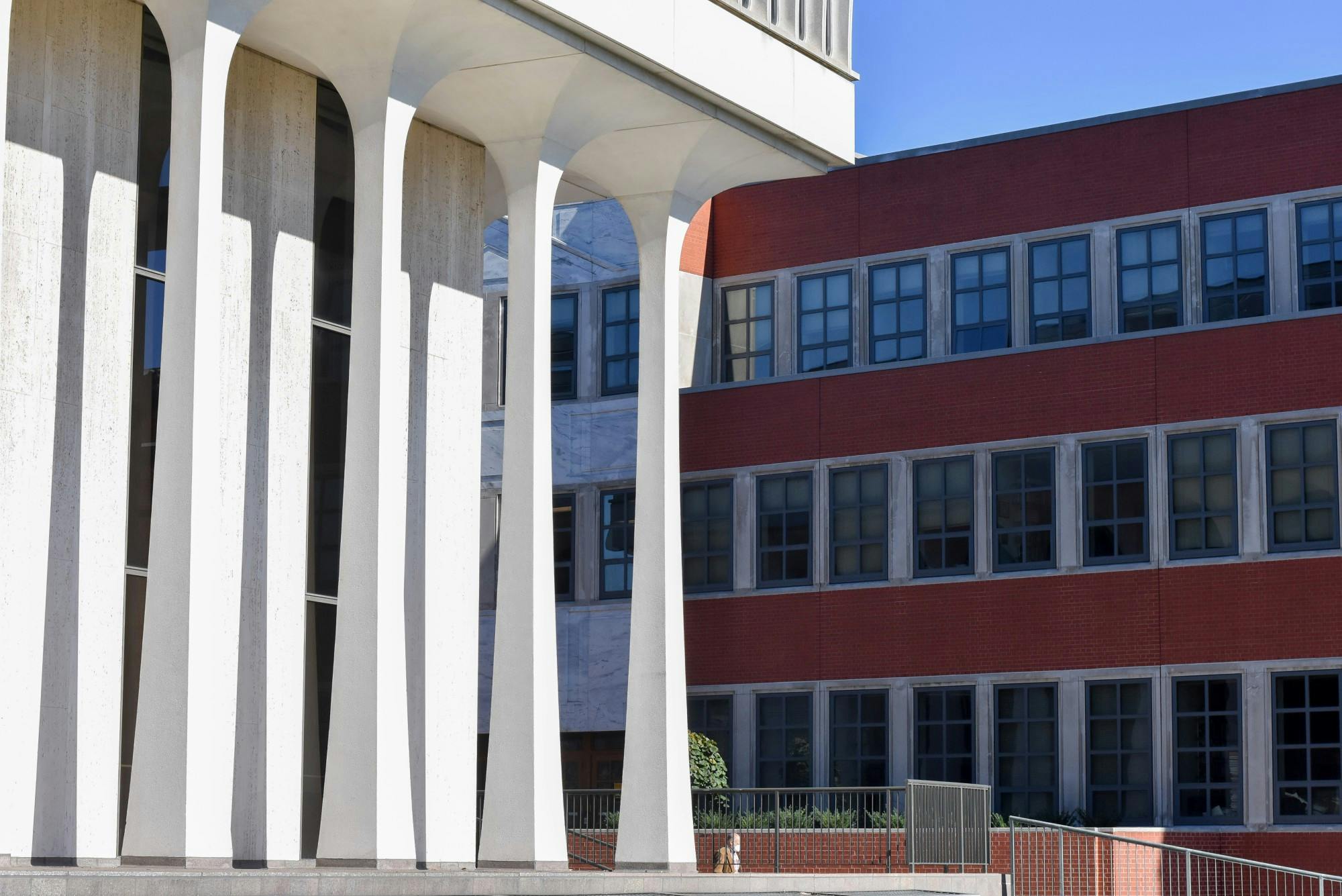 White building with modernist spires with corner profile on clear blue day next to a red brick building.