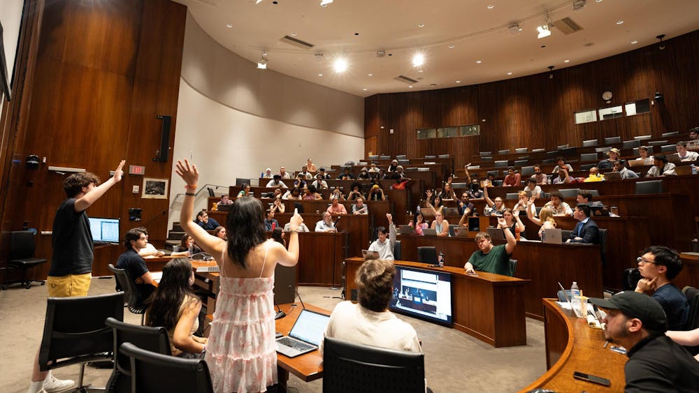 A large group of students in an auditorium with some students raising their hands to signal their affirmative votes.