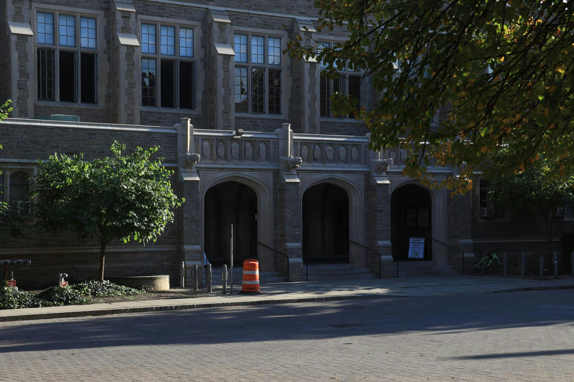 Gothic stone building with three archways and trees outside.