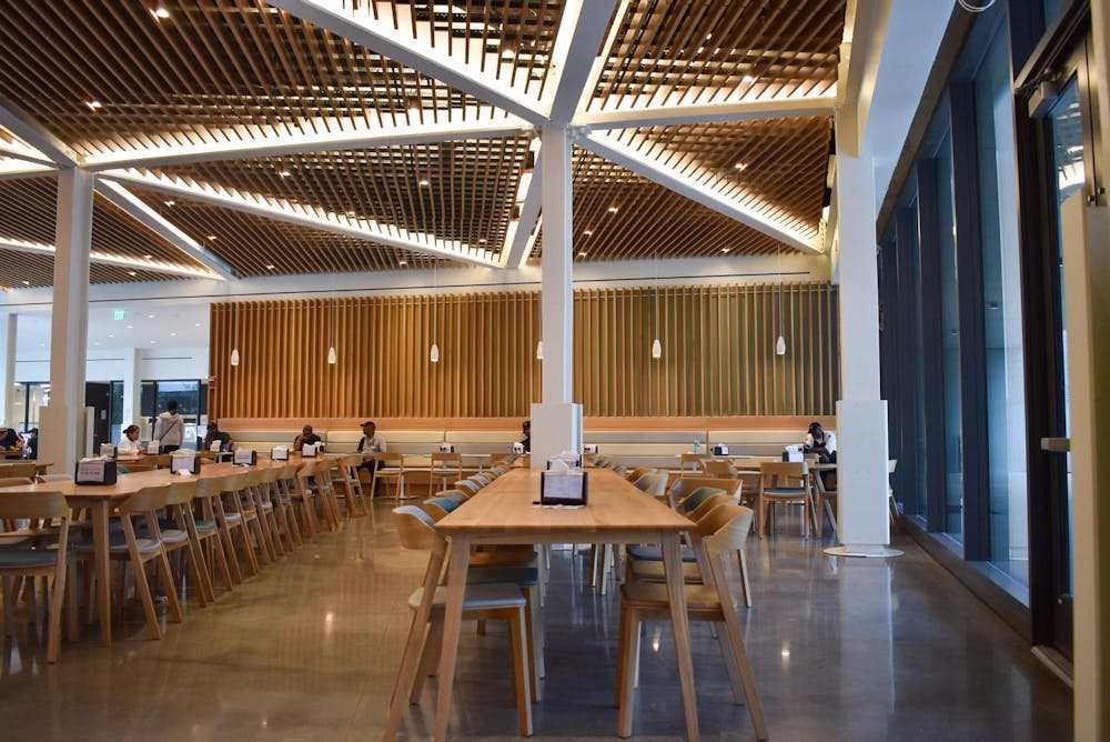 An open dining room with many tables and wood paneling.