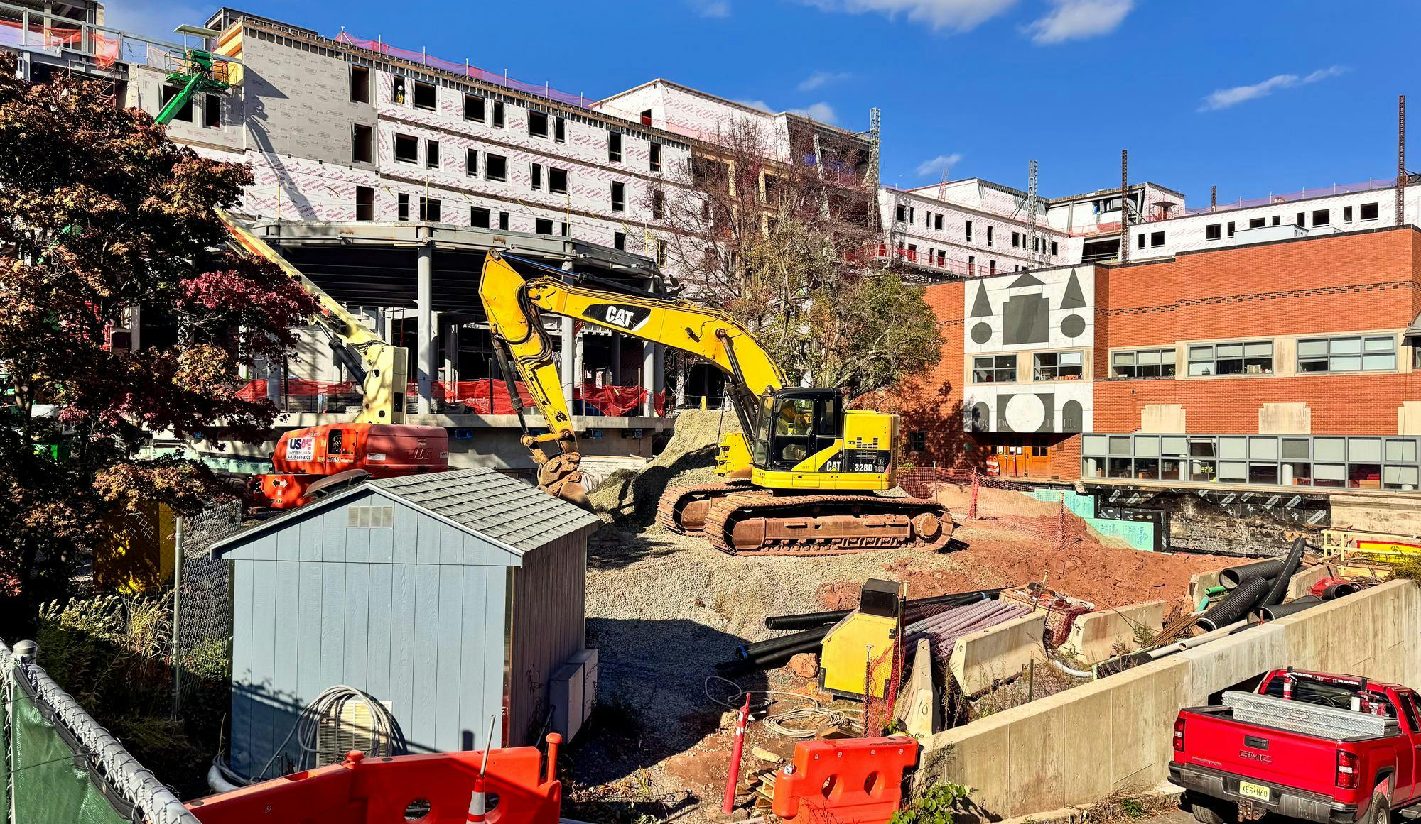 Construction is taking place in an area with a crane hovering over a pile of dirt as a building is being built in the background.  