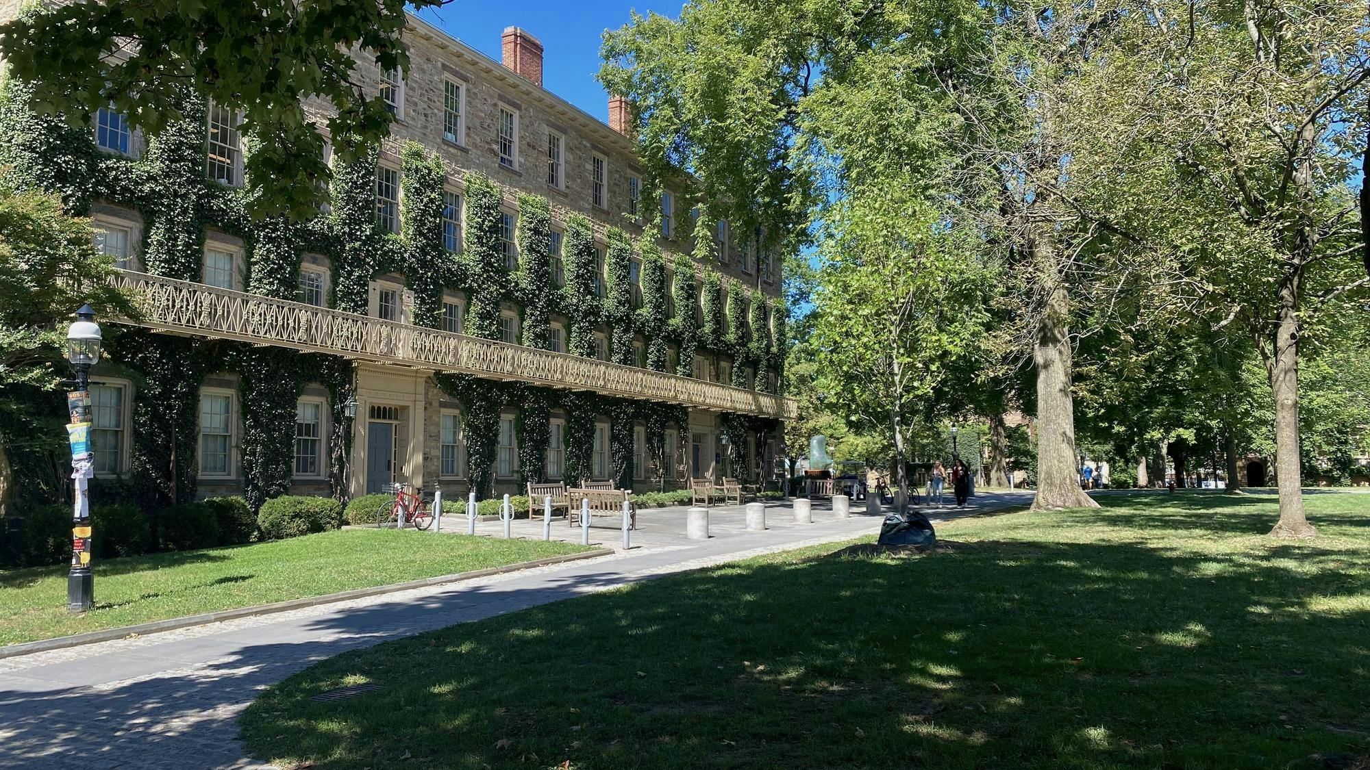 An ivy-covered building with shady trees in front.
