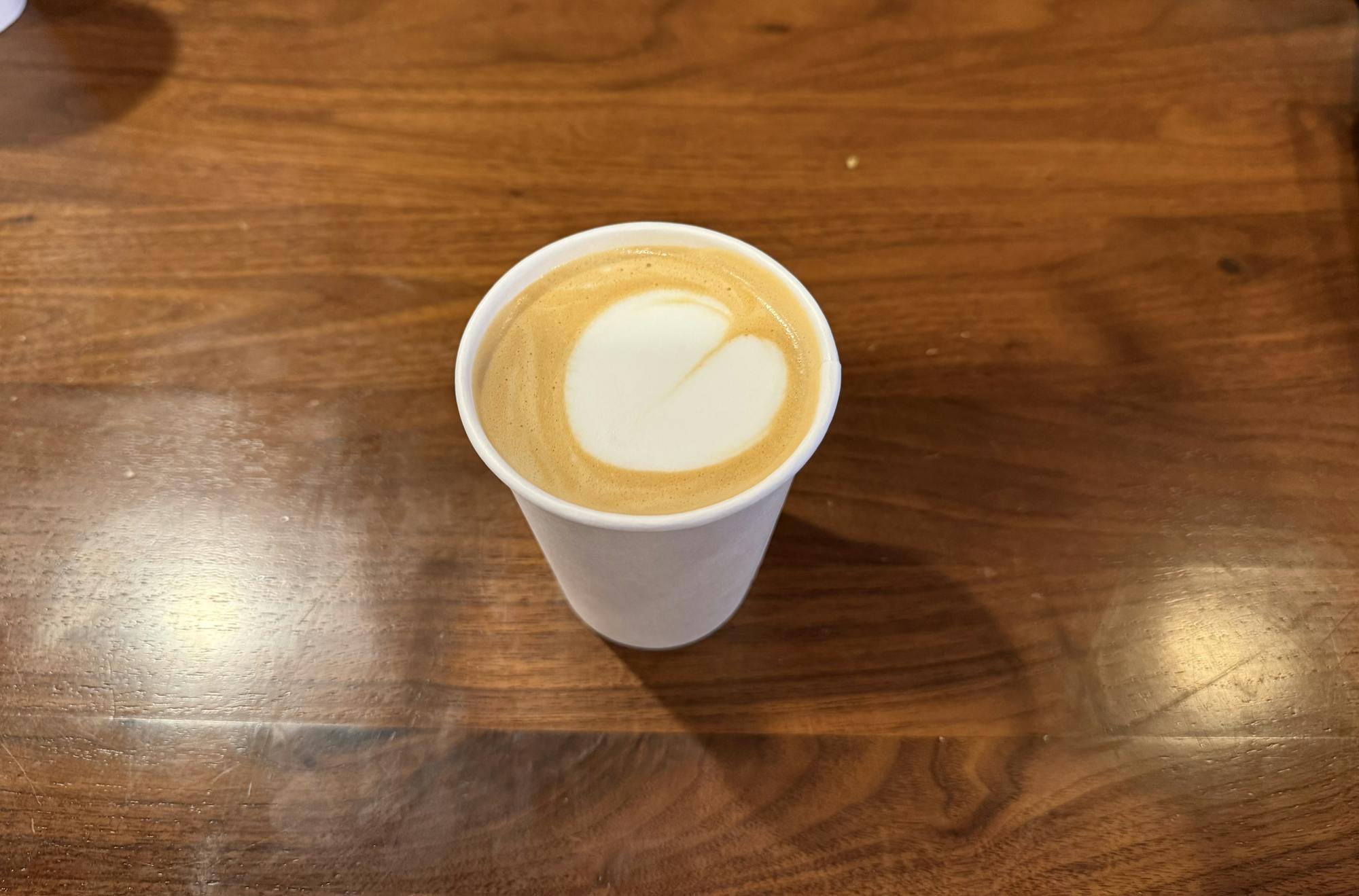 White cup with auburn coffee swirl sits on a wooden table