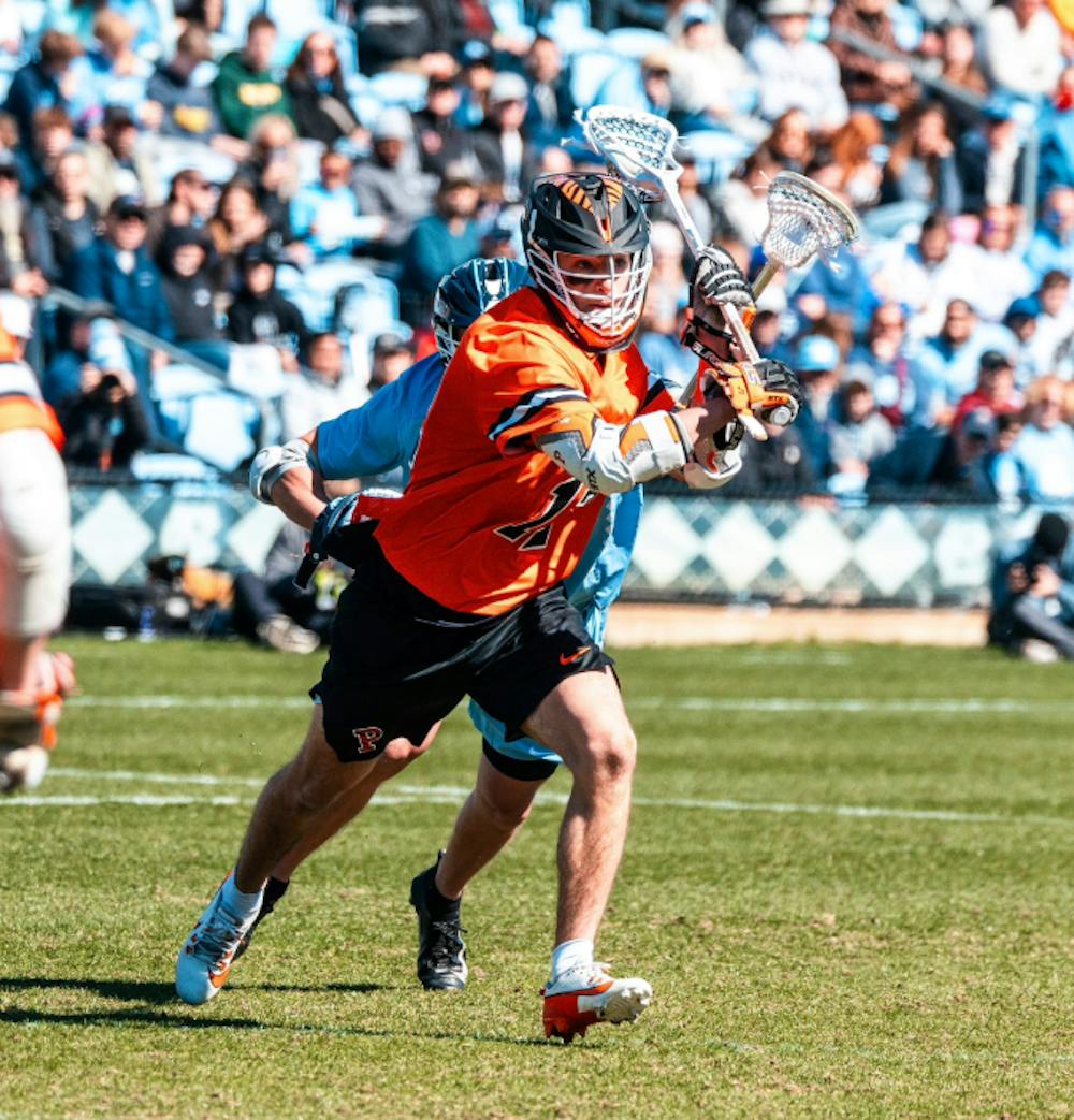 Lacrosse player running for the ball in front of a crowd.