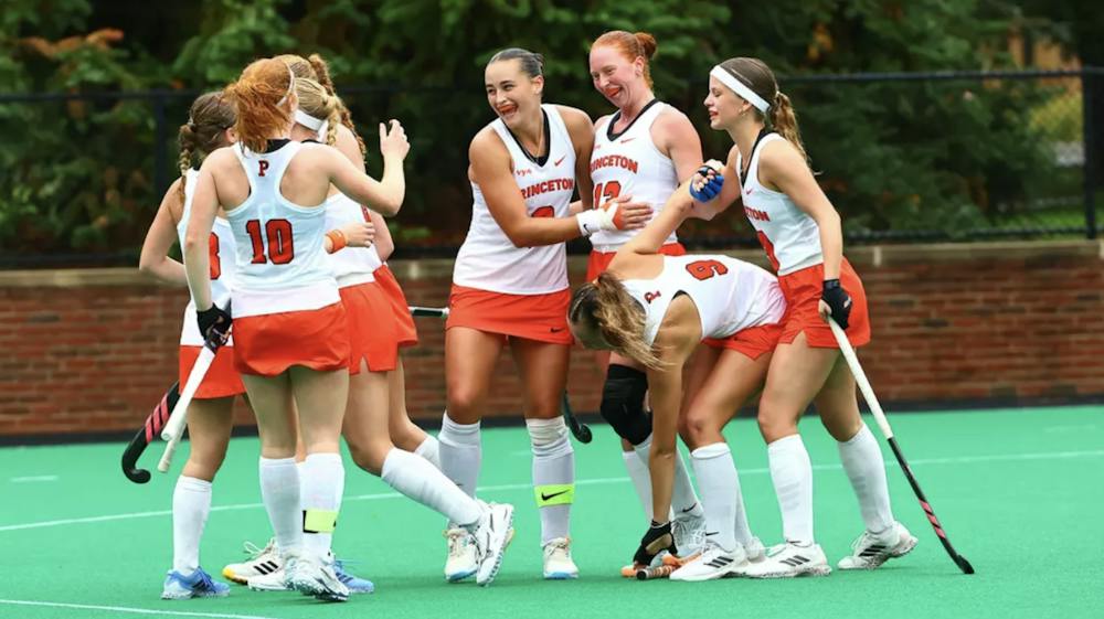 A team in white and orange jerseys celebrating after a goal