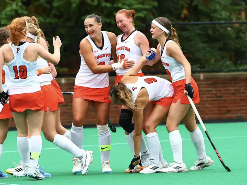 A team in white and orange jerseys celebrating after a goal