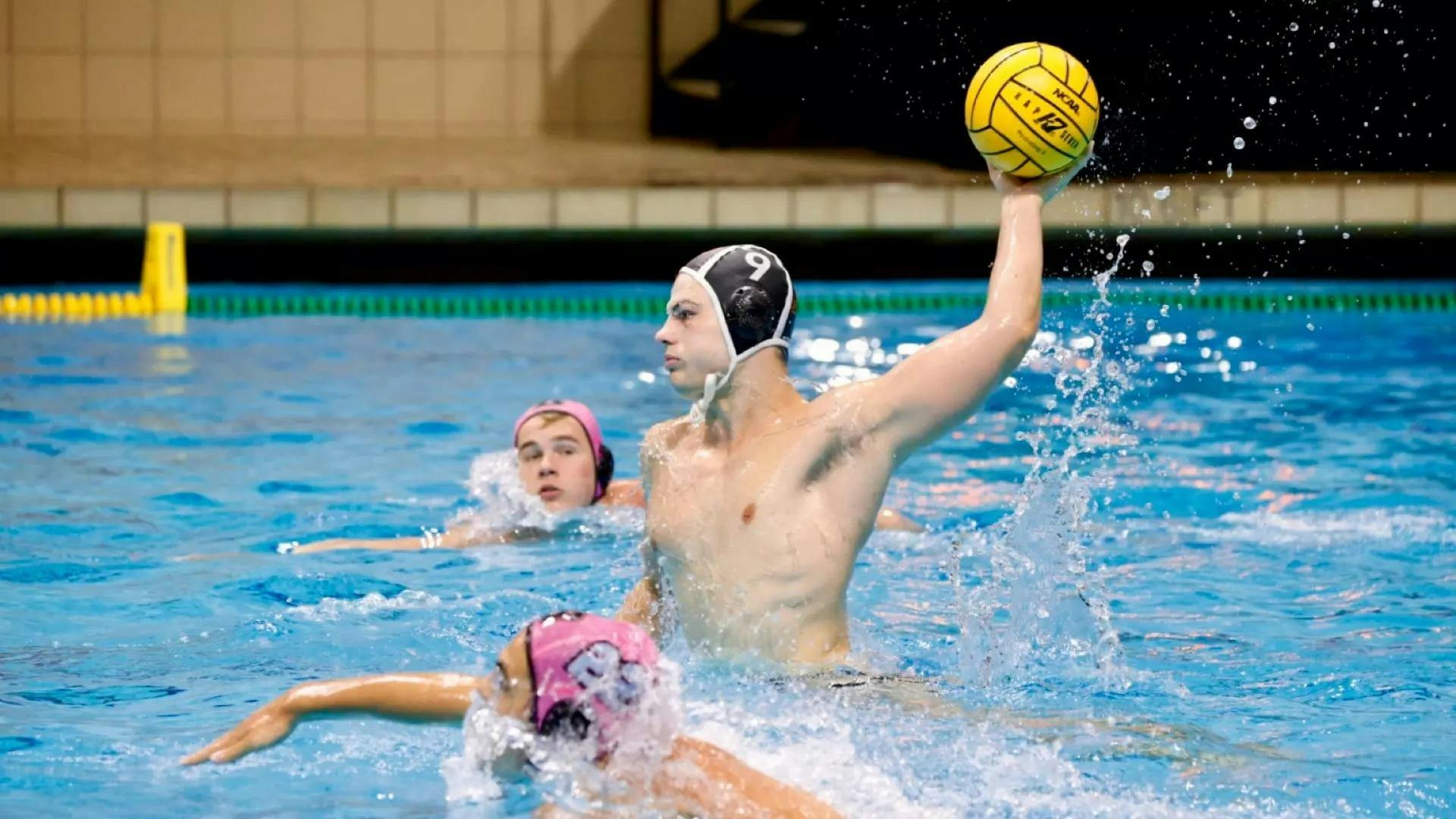 A men’s water polo player launching the ball.