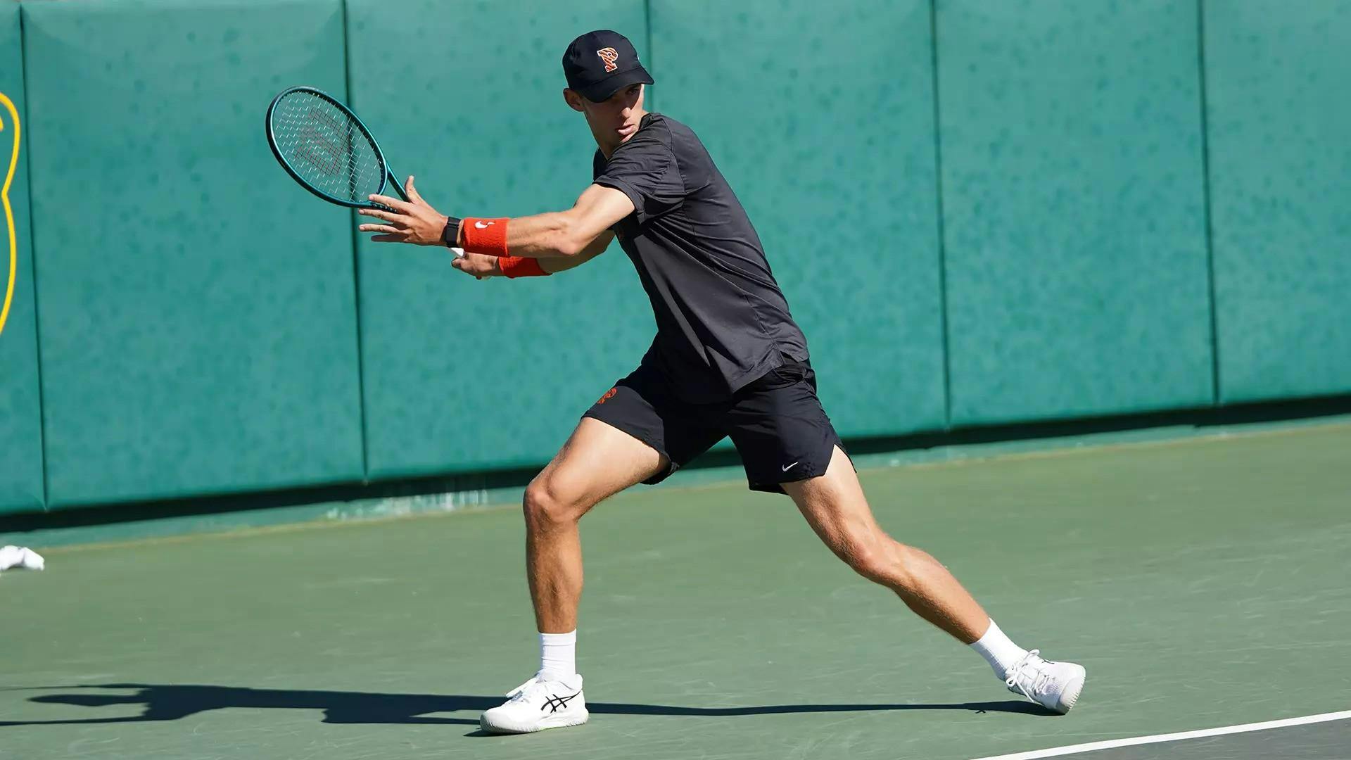 A man with a tennis racket in his hand on a hard playing surface. 