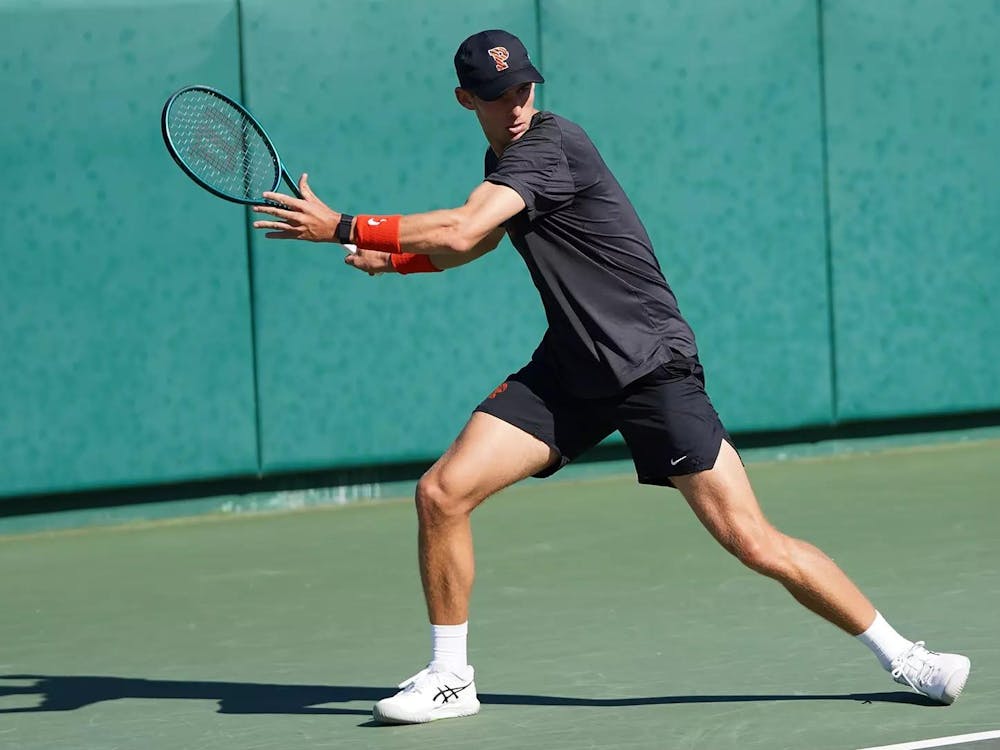 A man with a tennis racket in his hand on a hard playing surface.