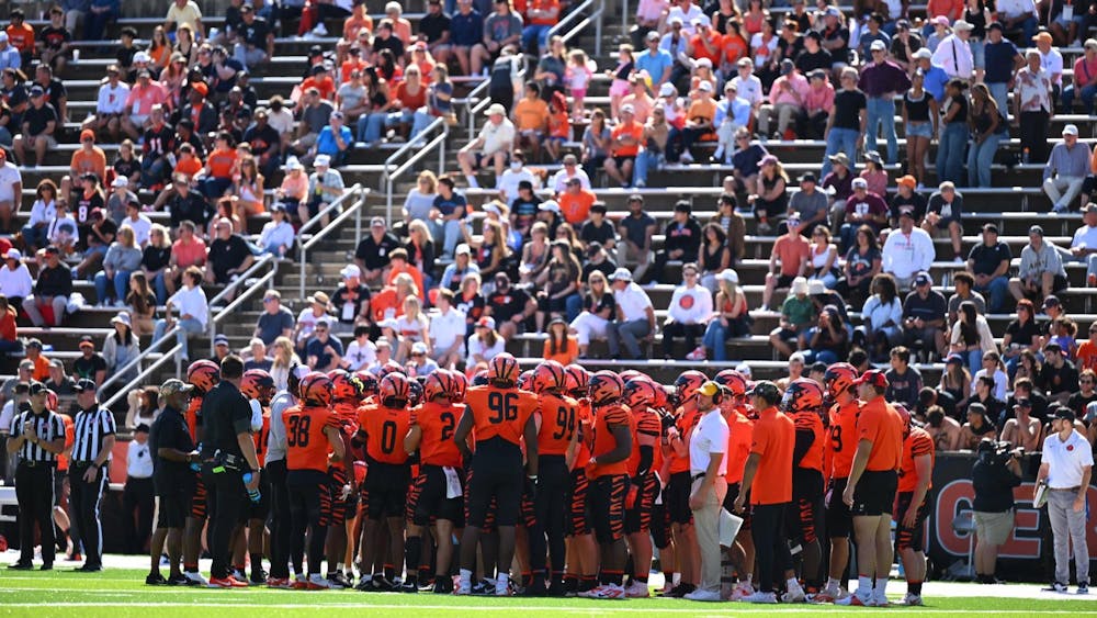 Football players in orange jerseys huddle up.
