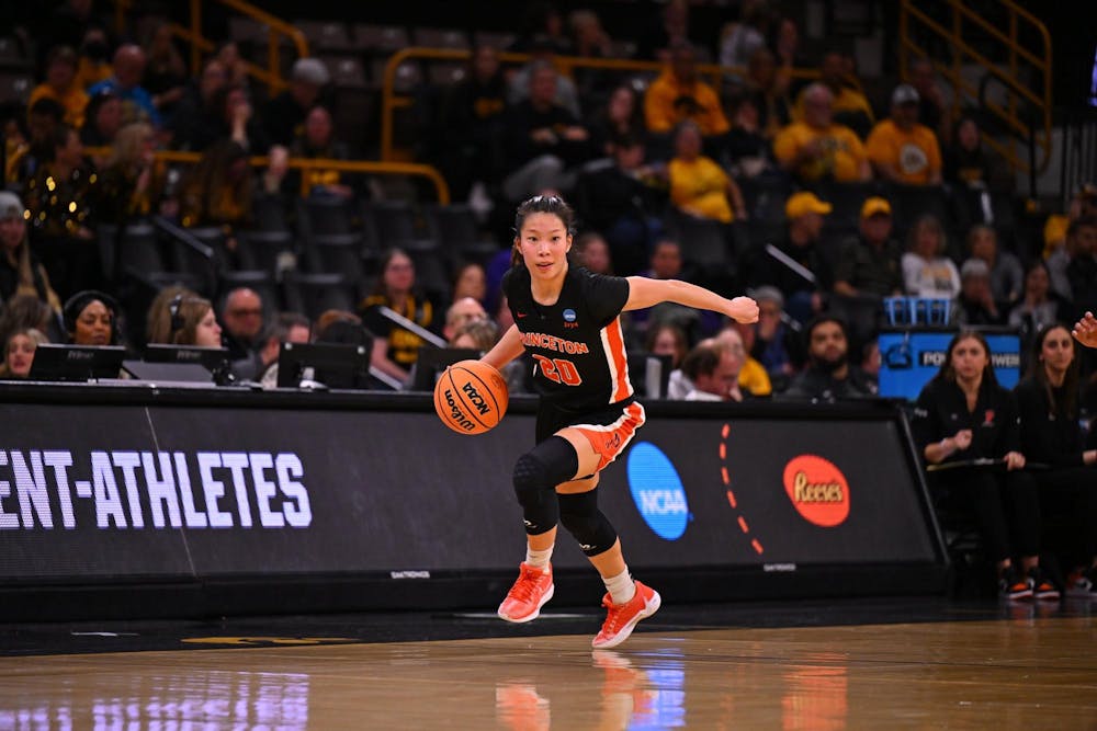Player in black and orange Princeton uniform dribbles ball up basketball court. 