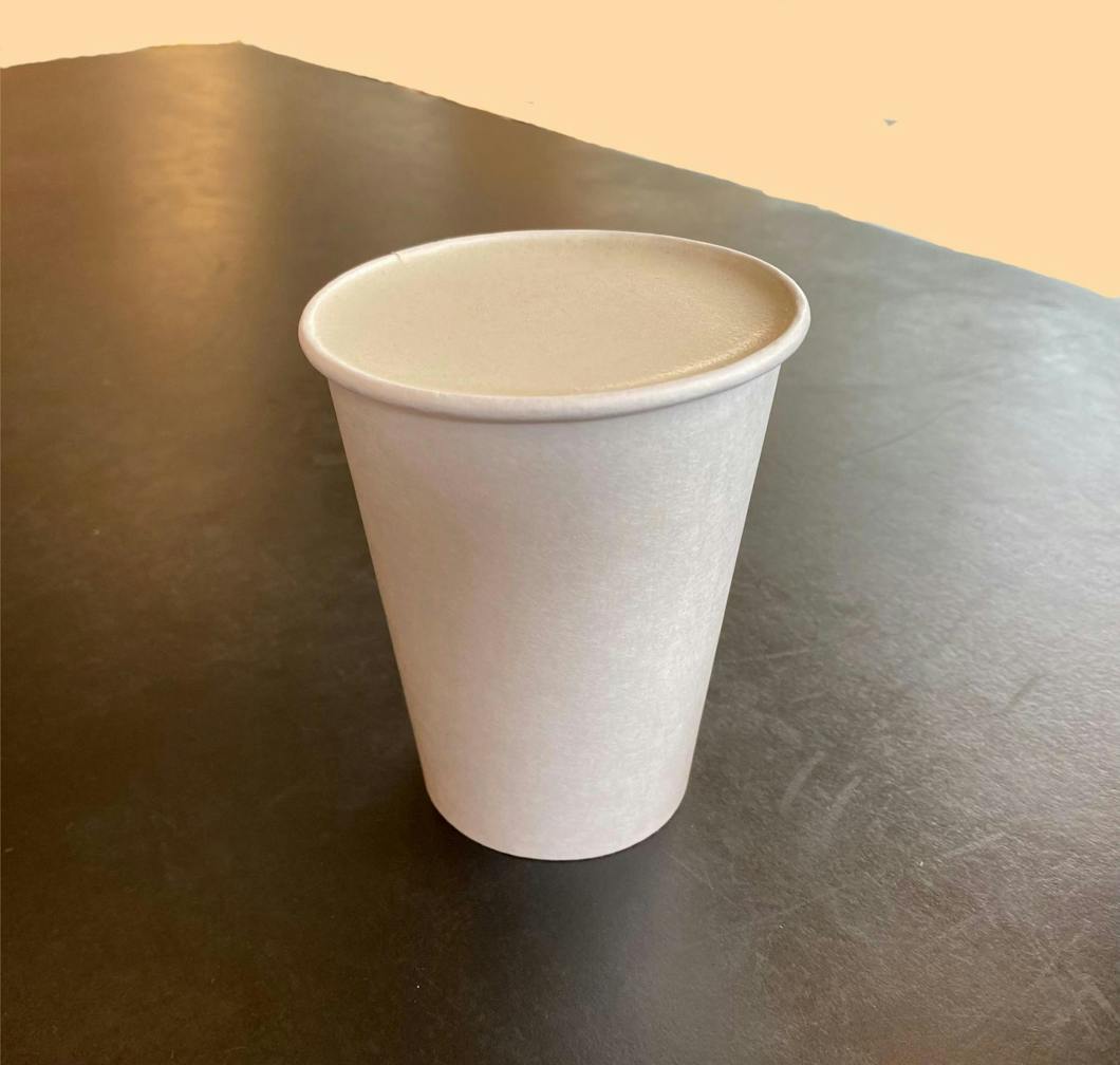 A warm cup of mate fog sits on a table in front of a light orange background. 