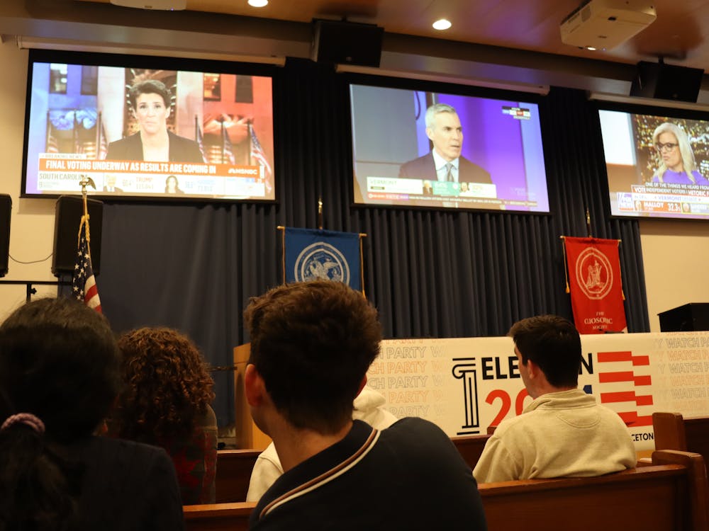 Three screens are at the top of the image, showing three different political shows. A group of students are clustered around, watching.