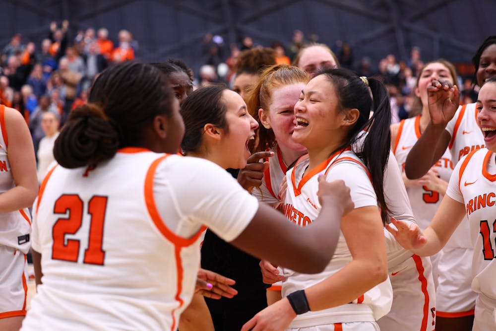 Ashley Chea in white and orange jersey surrounded by her teammates in celebration.