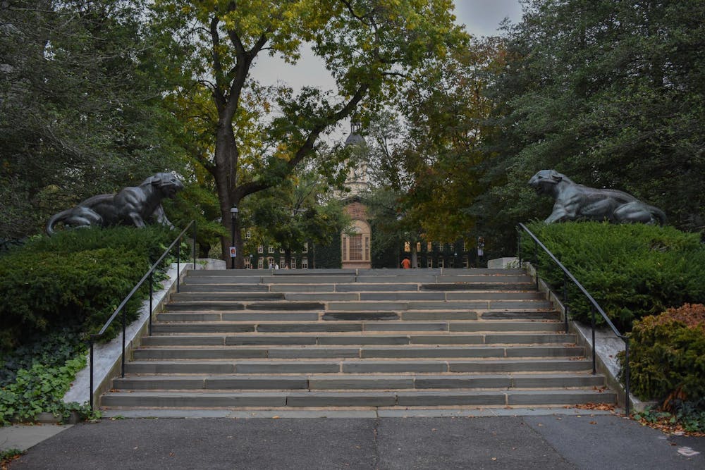 A flight of stairs, flanked by two tiger statues, oversees a distant building. 
