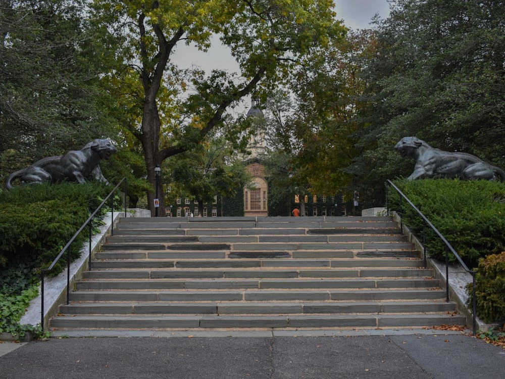 A flight of stairs, flanked by two tiger statues, oversees a distant building. 