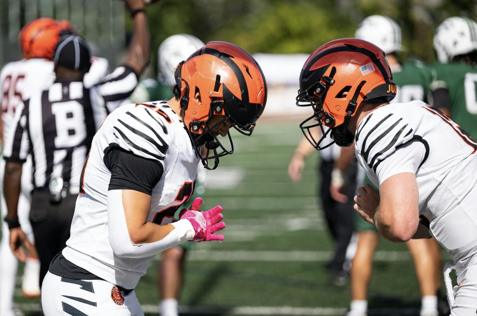 Two football players in white jerseys bow to each other.