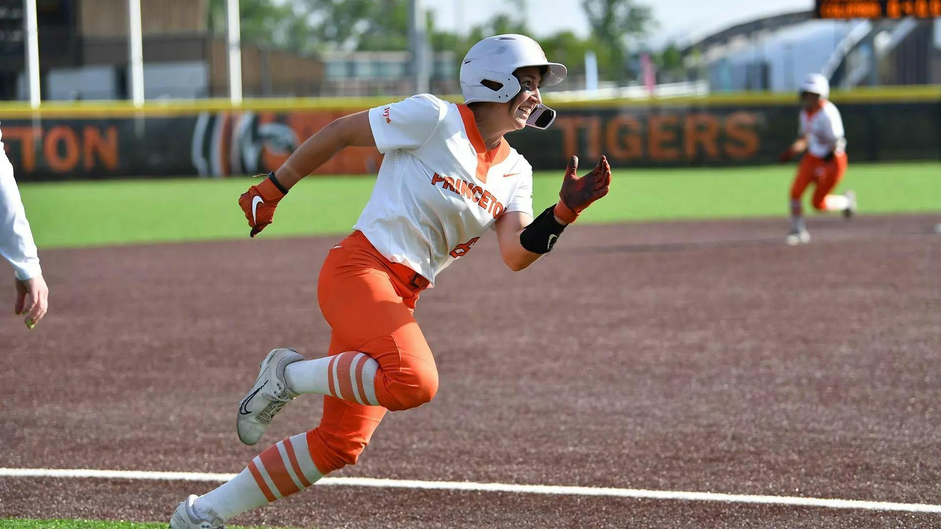 A women running on a softball fielding where orange and white. 