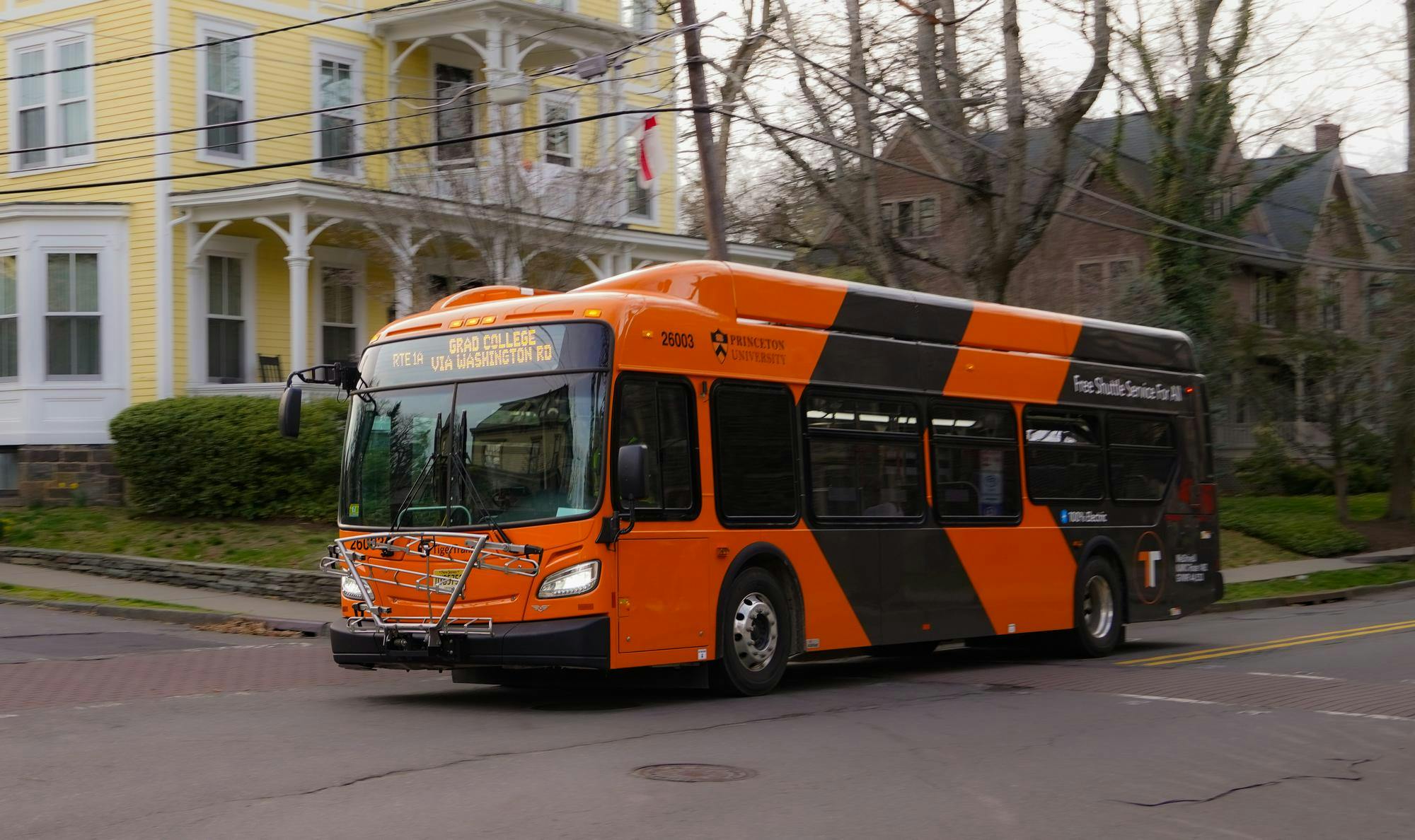 Orange TigerTransit bus traveling near a residential area.
