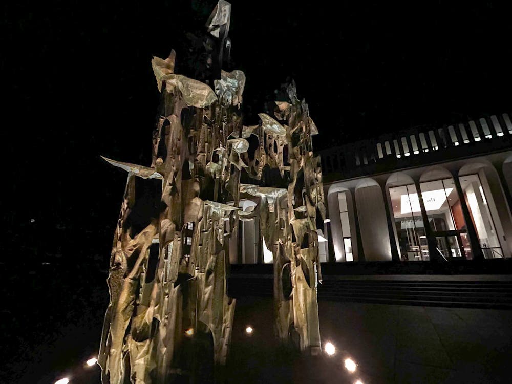 The large metal sculpture in front of the SPIA building is lit up at night.
