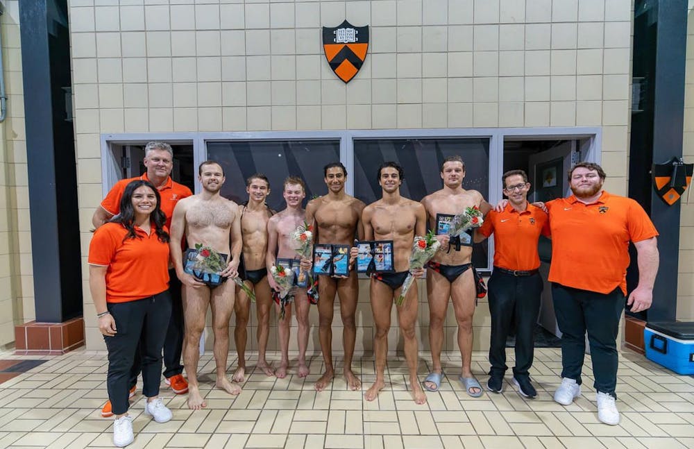 Seniors on water polo pose for team picture with framed photos