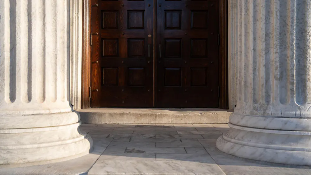 A brown door in the middle is flanked by white columns on both sides.