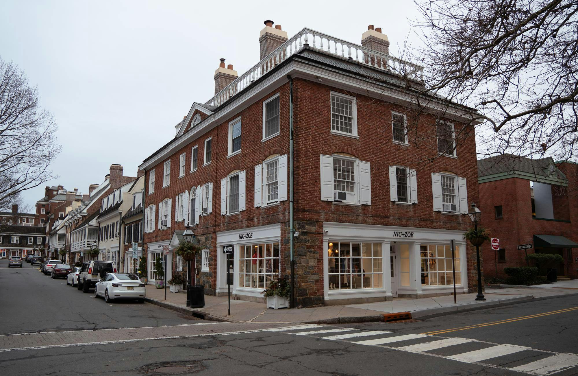 A brick building with the clothing store "Nic+Zoe" stands on the corner of a street in Palmer Square. 