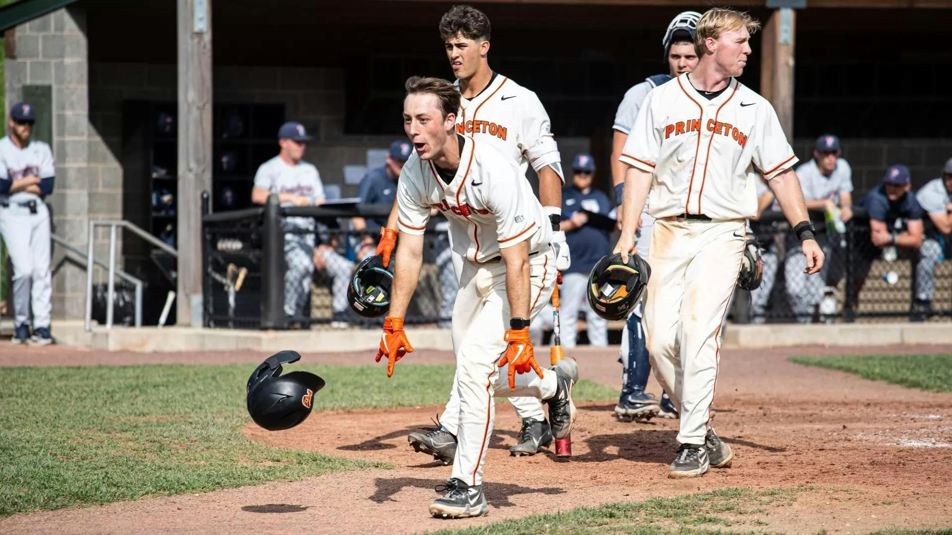 Princeton baseball player in a white jersey celebrates and runs into the field.