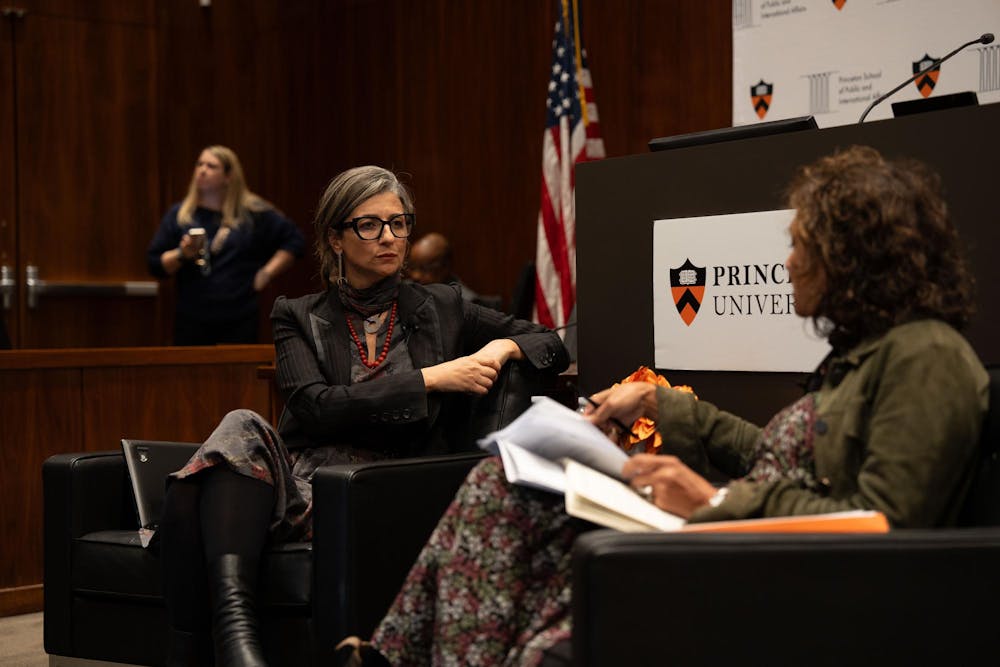 Two women talking to each other, sitting on sofas on a stage.