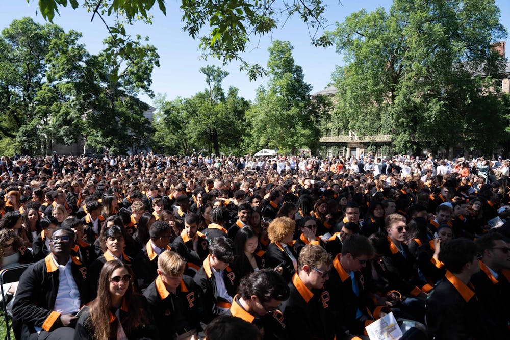 Several hundred people sit in a field.